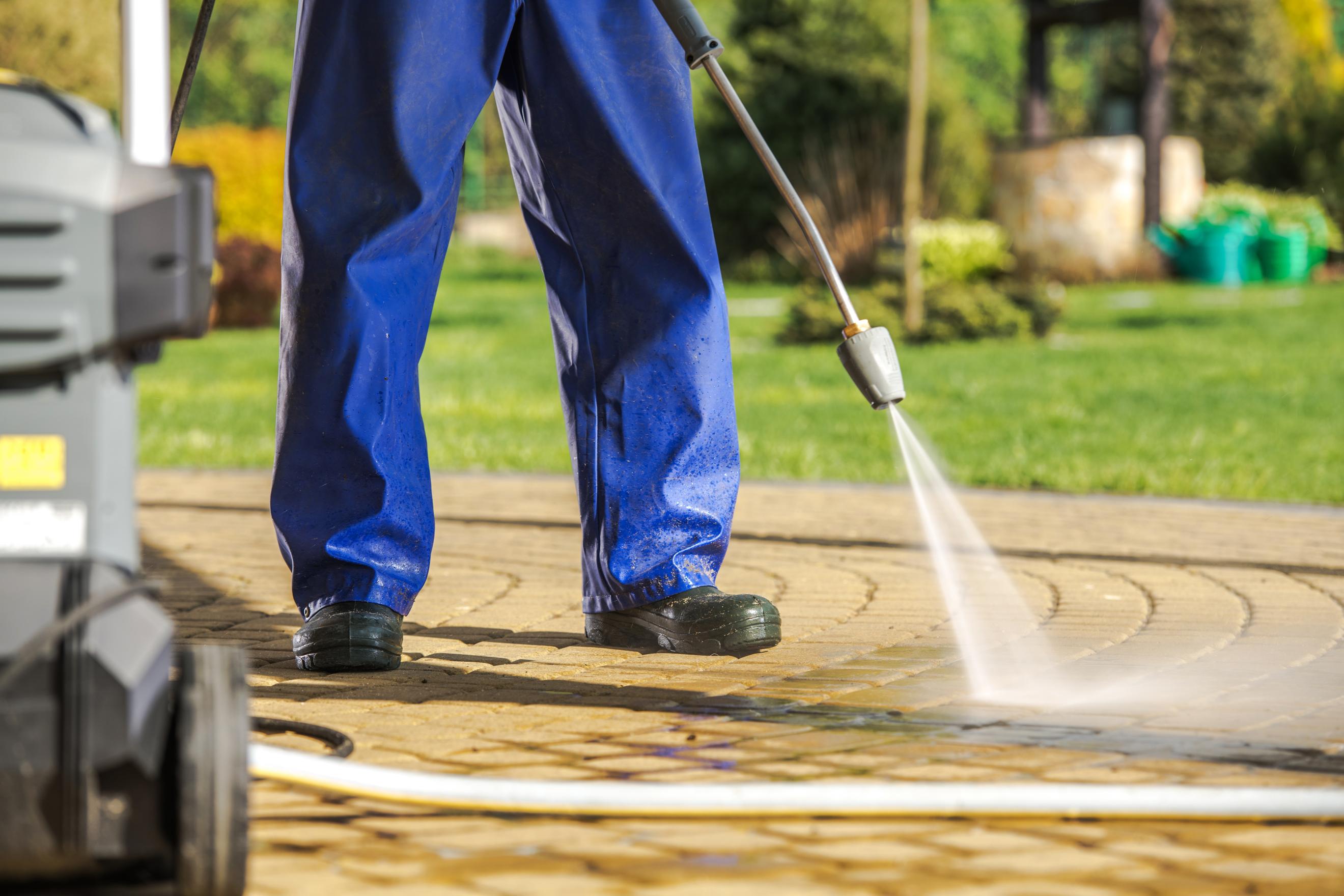 Technician pressure washing a concrete driveway in Boulder County to remove dirt and grime